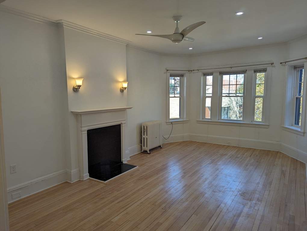 an empty room with wooden floor fireplace and windows