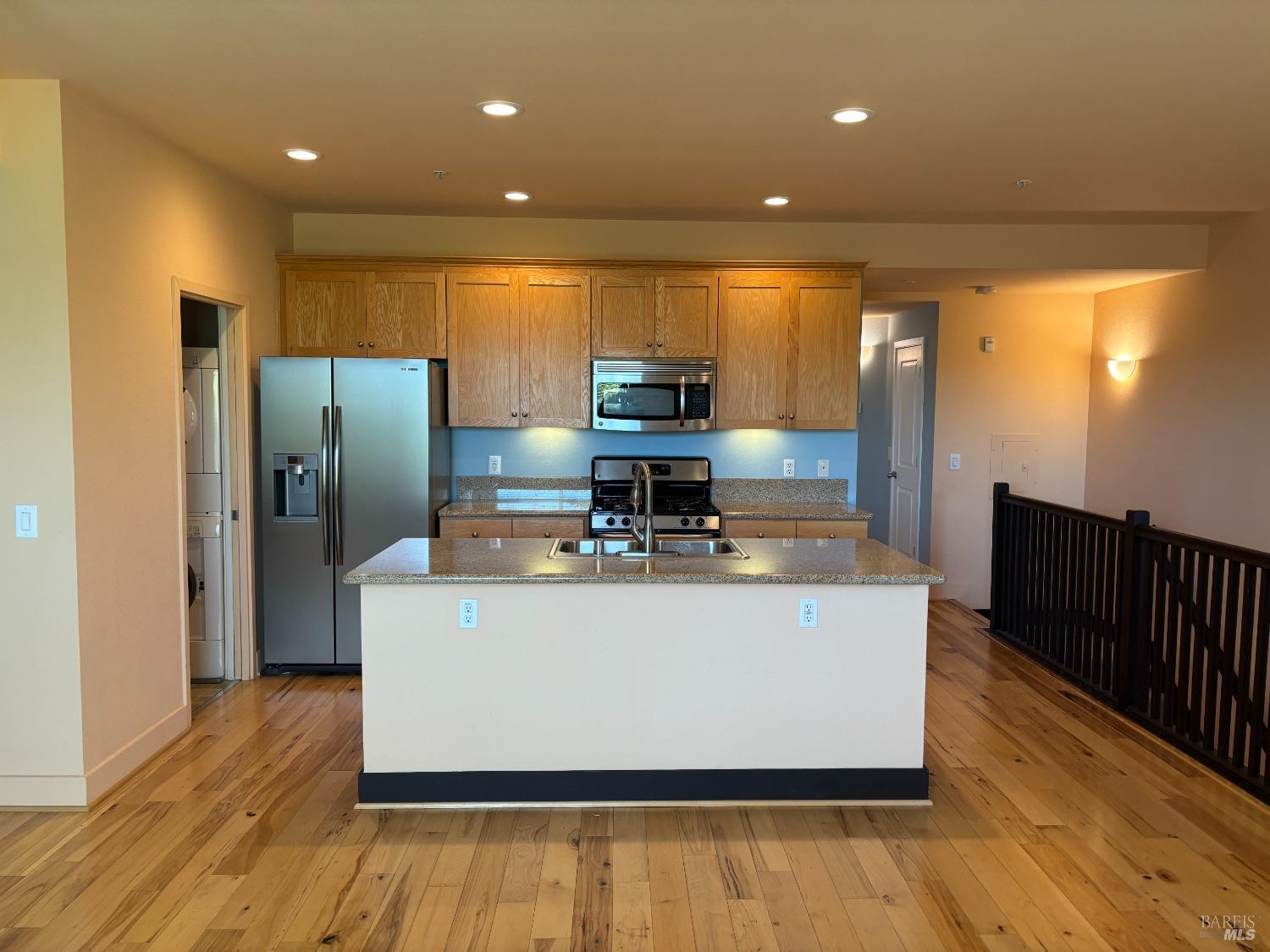 a view of kitchen with stainless steel appliances wooden floor and large window