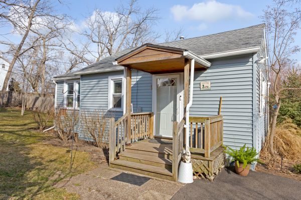 a view of wooden house with a small yard and plants