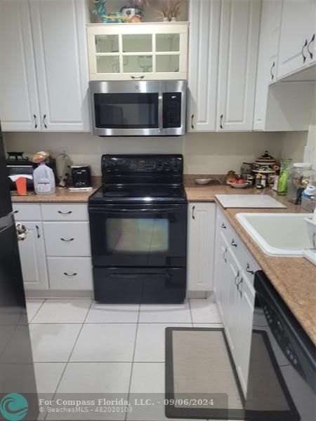 a kitchen with granite countertop a stove a sink and a microwave