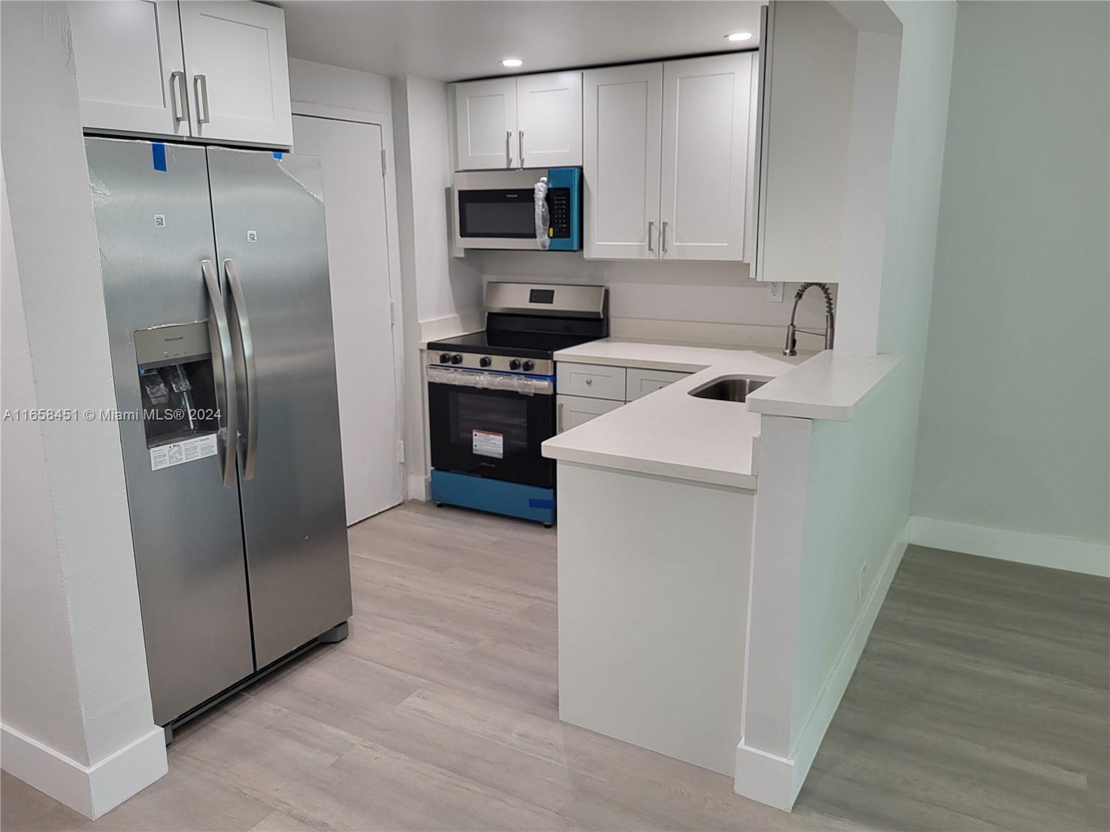 a kitchen with stainless steel appliances a refrigerator sink and microwave