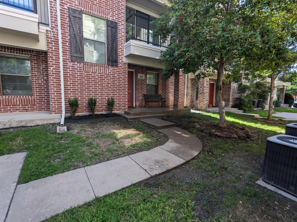 a view of a brick house with a yard and large tree