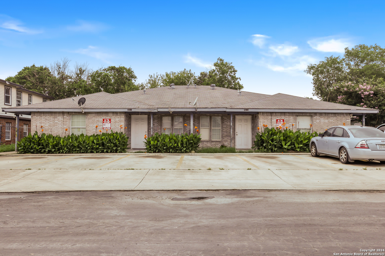 front view of a house with a yard and a car parked area