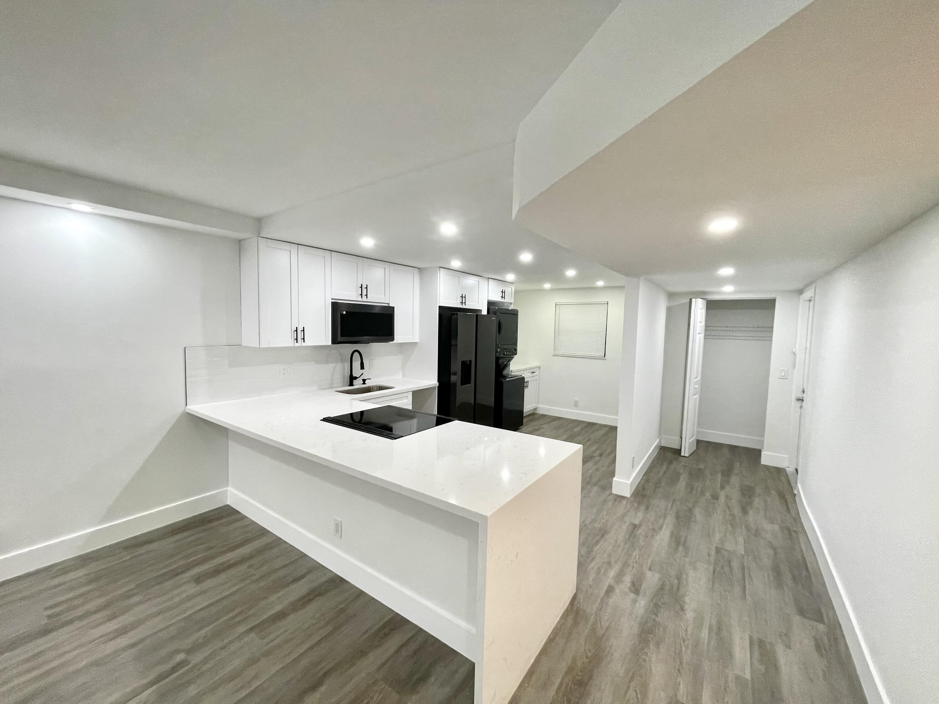 a large white kitchen with a sink and dishwasher a oven with wooden floor