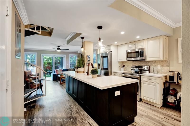 a large kitchen with kitchen island a sink a counter space and stainless steel appliances