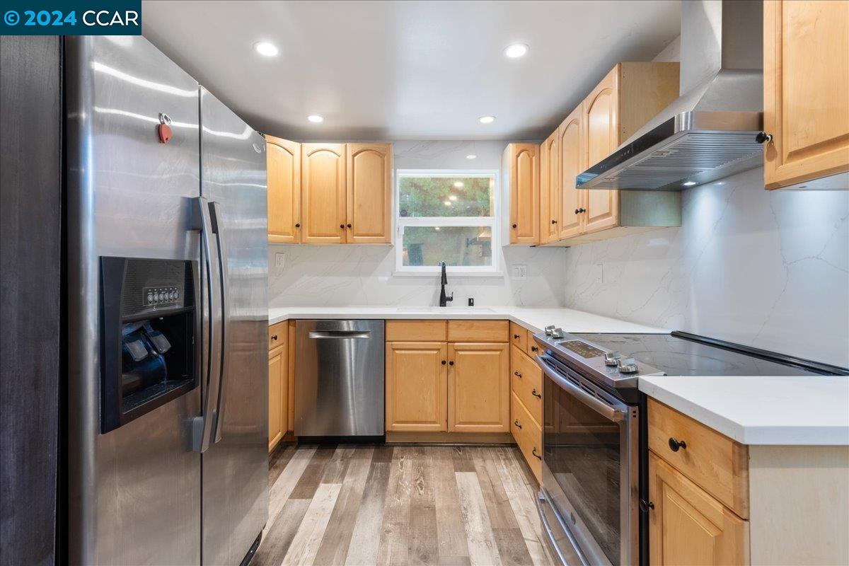 a kitchen with stainless steel appliances granite countertop a sink a stove and a refrigerator