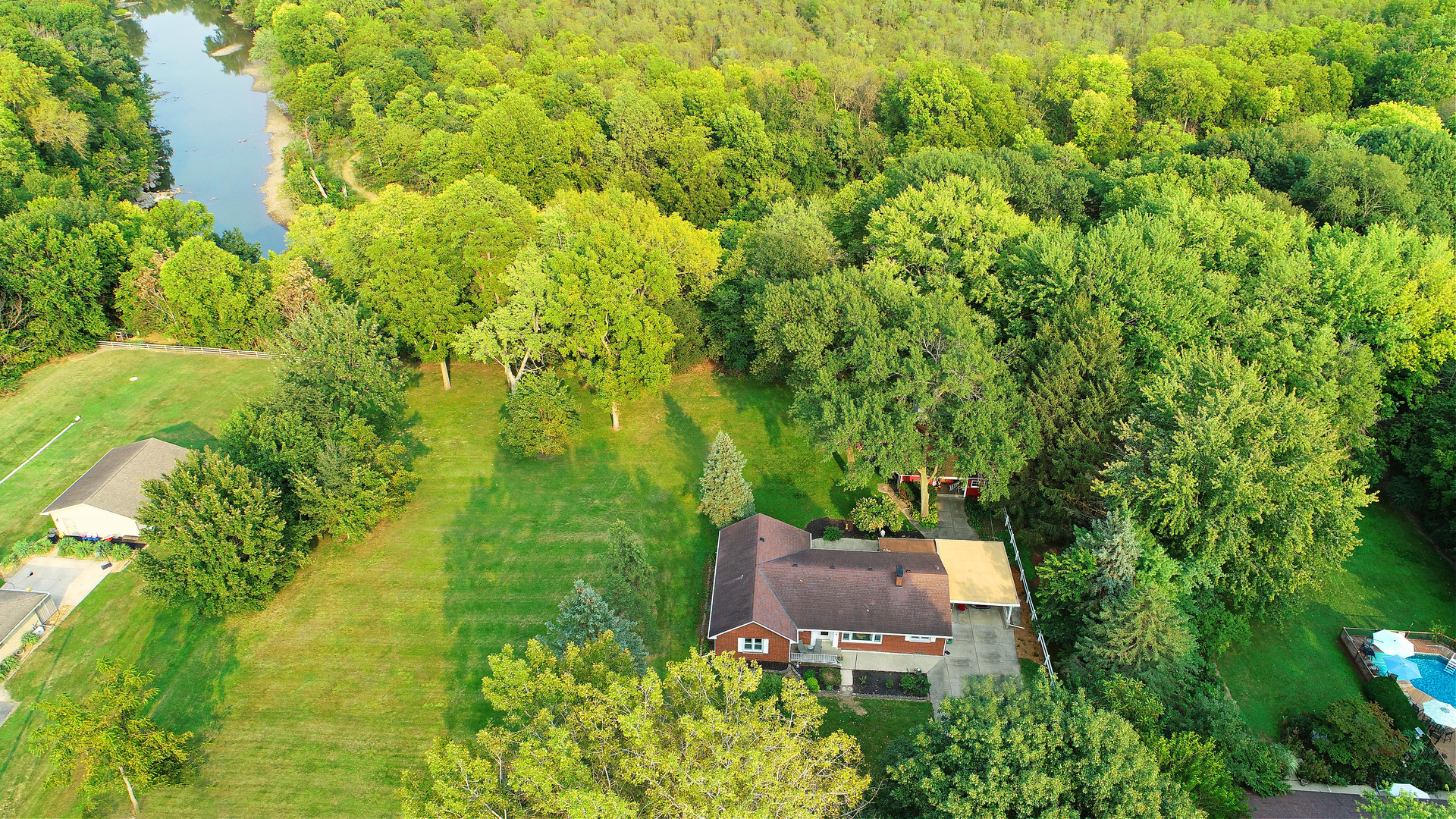 an aerial view of residential house with outdoor space and trees all around