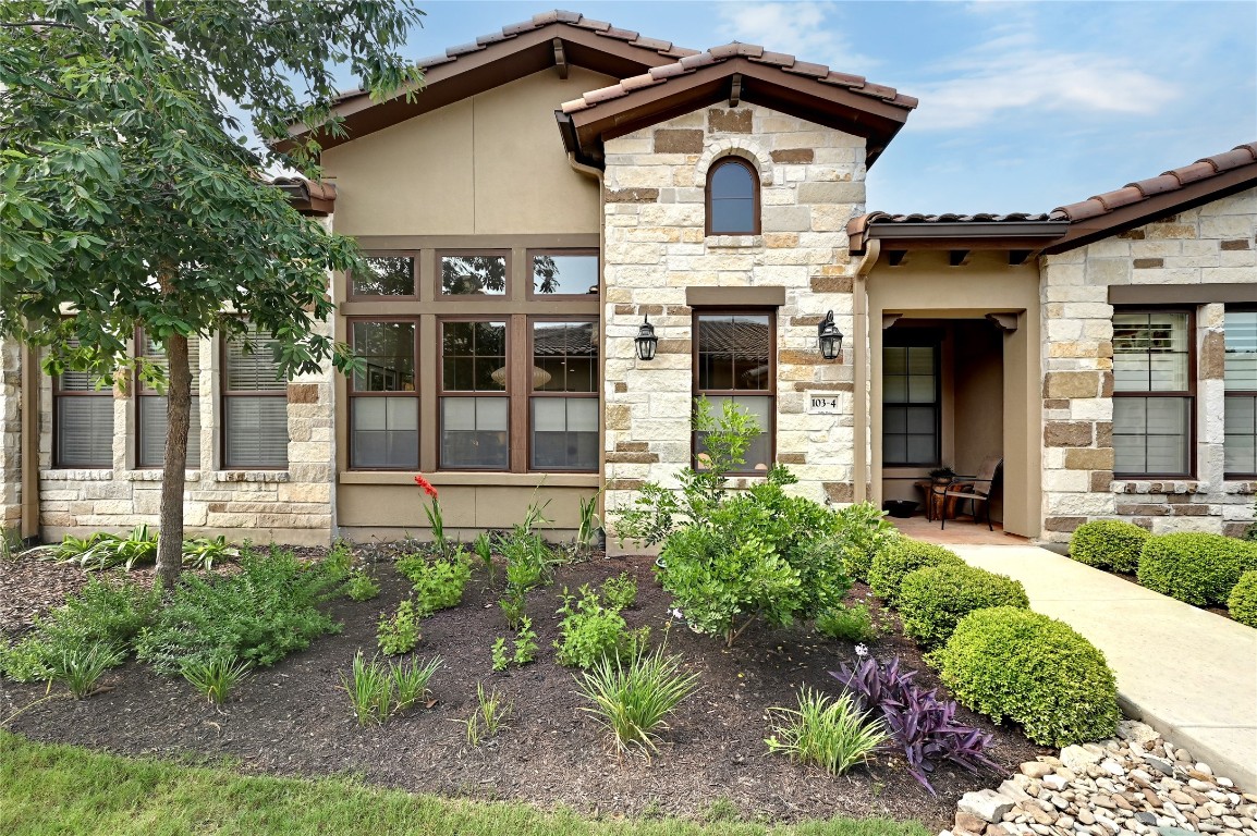 a view of a house with a small yard plants and large tree