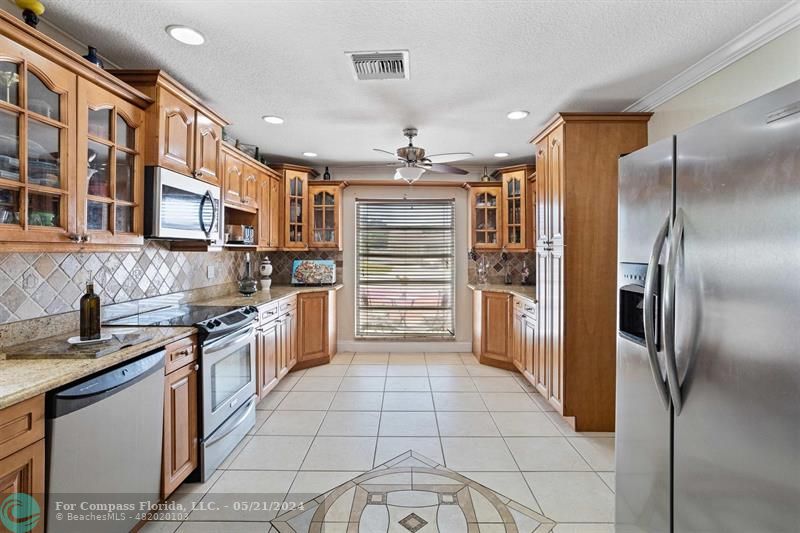 a kitchen with granite countertop a refrigerator and a stove top oven