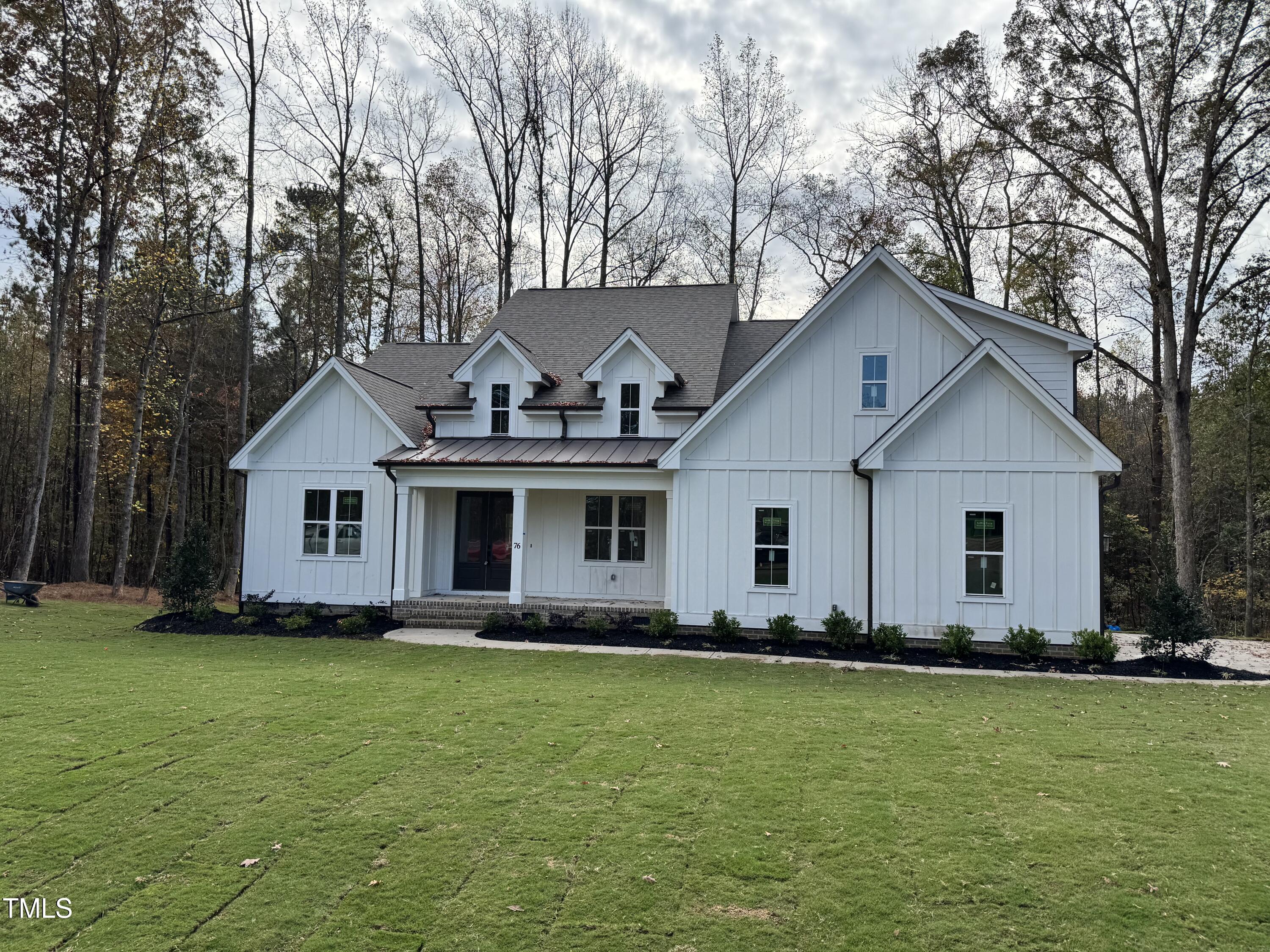 a front view of house with yard and trees in the background