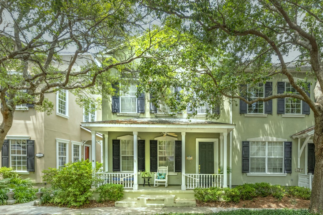 front view of a brick house with a large windows and a large tree