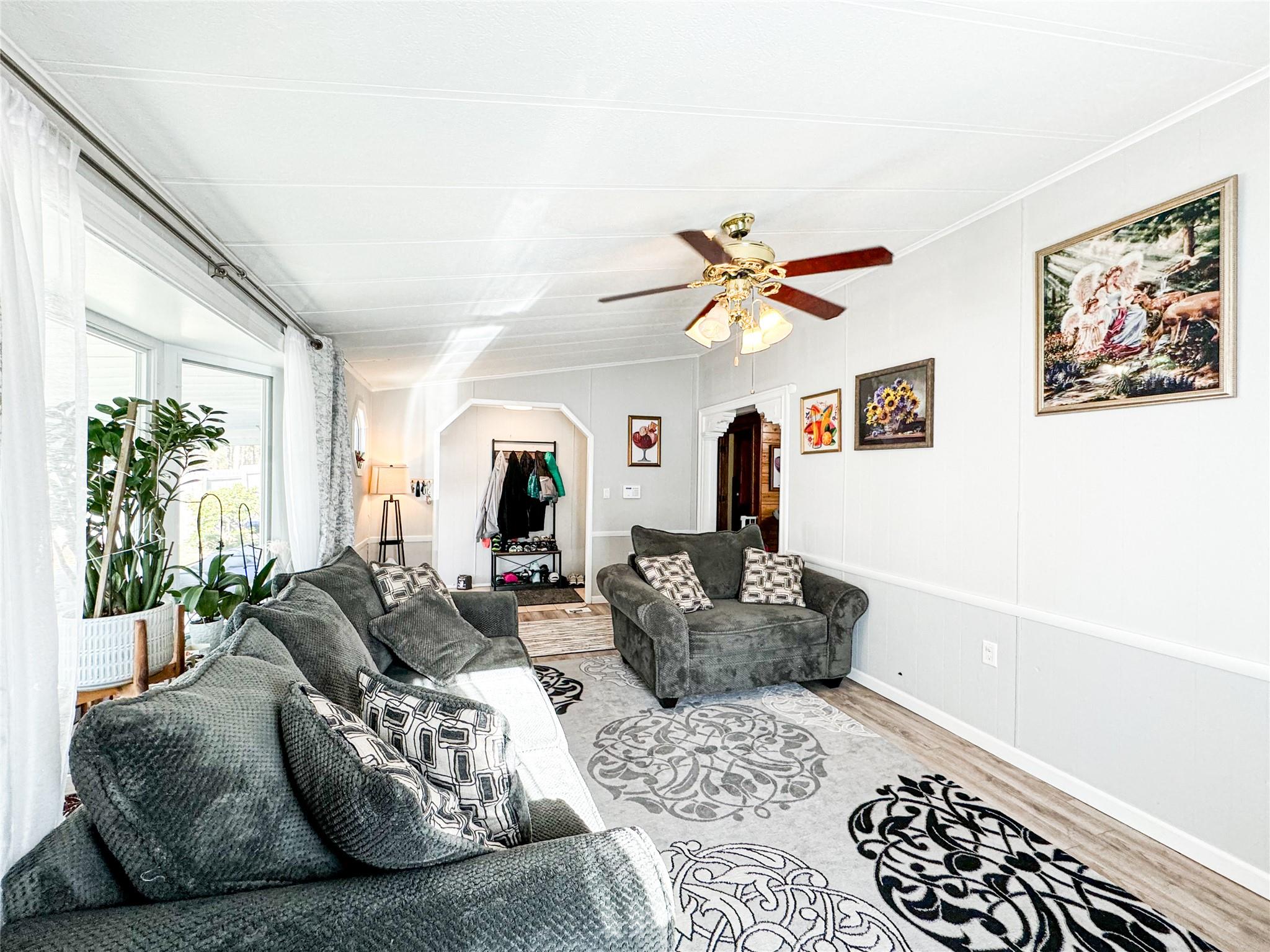 Living room featuring ceiling fan, ornamental molding, and hardwood / wood-style flooring