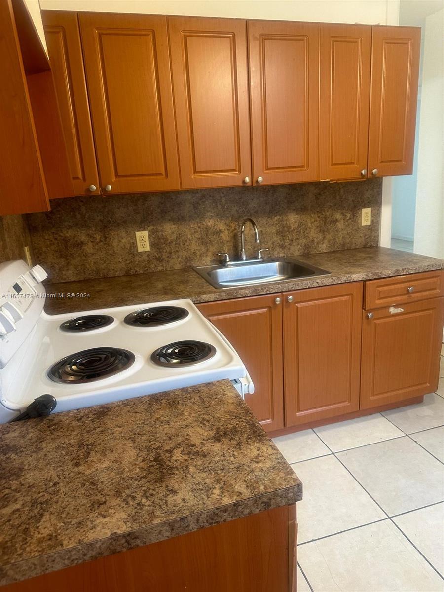 a kitchen with granite countertop a sink a stove and cabinets