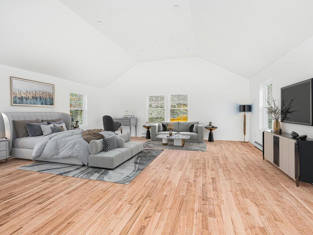 Primary Bedroom featuring En Suite & light hardwood / wood-style flooring and lofted ceiling