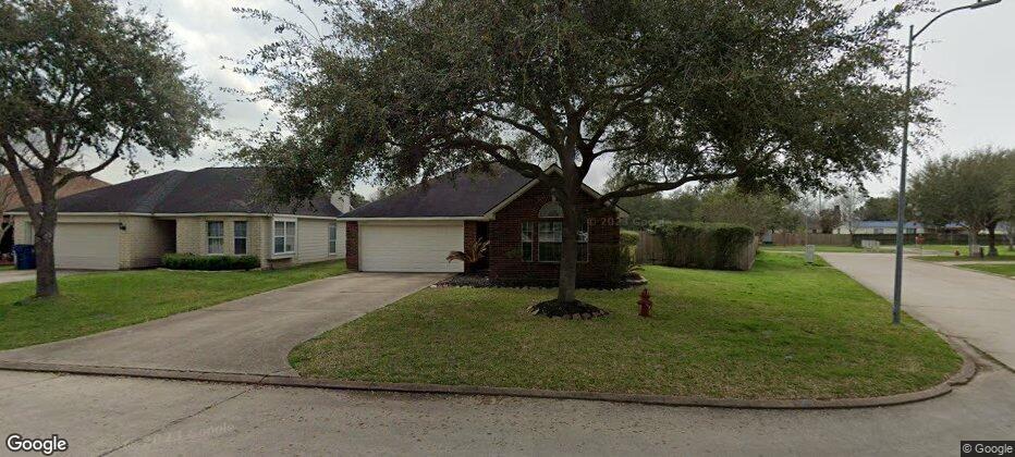 a view of a white house next to a yard with big trees