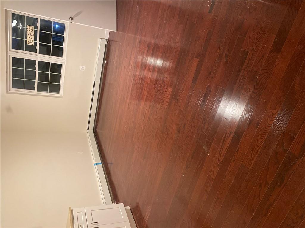 Empty room with baseboard heating and dark hardwood / wood-style flooring