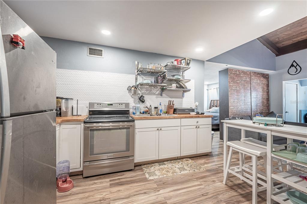 a kitchen with a stove a refrigerator and white cabinets