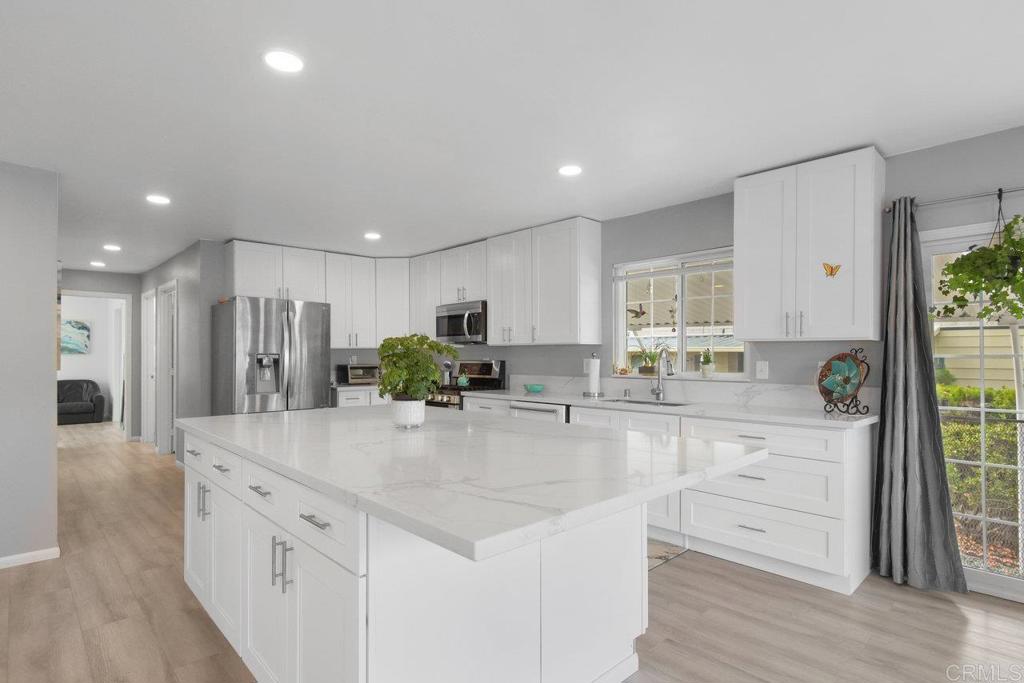 a large kitchen with kitchen island white cabinets and stainless steel appliances