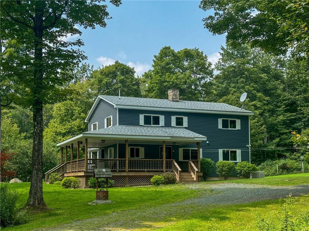 View of front facade with covered porch, central AC, and a front yard