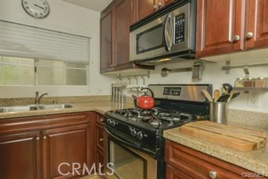 a kitchen with stainless steel appliances granite countertop a stove a sink and a microwave