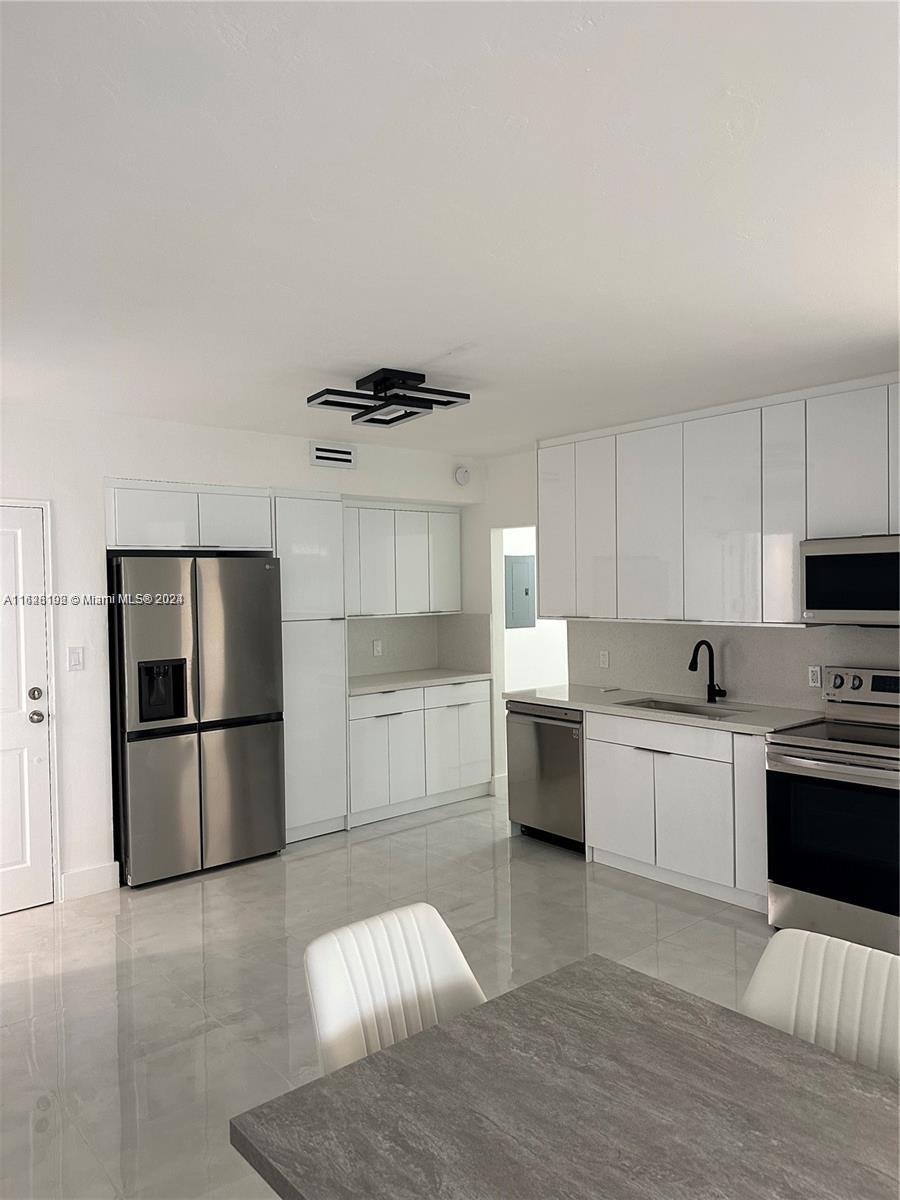 a kitchen with stainless steel appliances a refrigerator a stove a sink and white cabinets