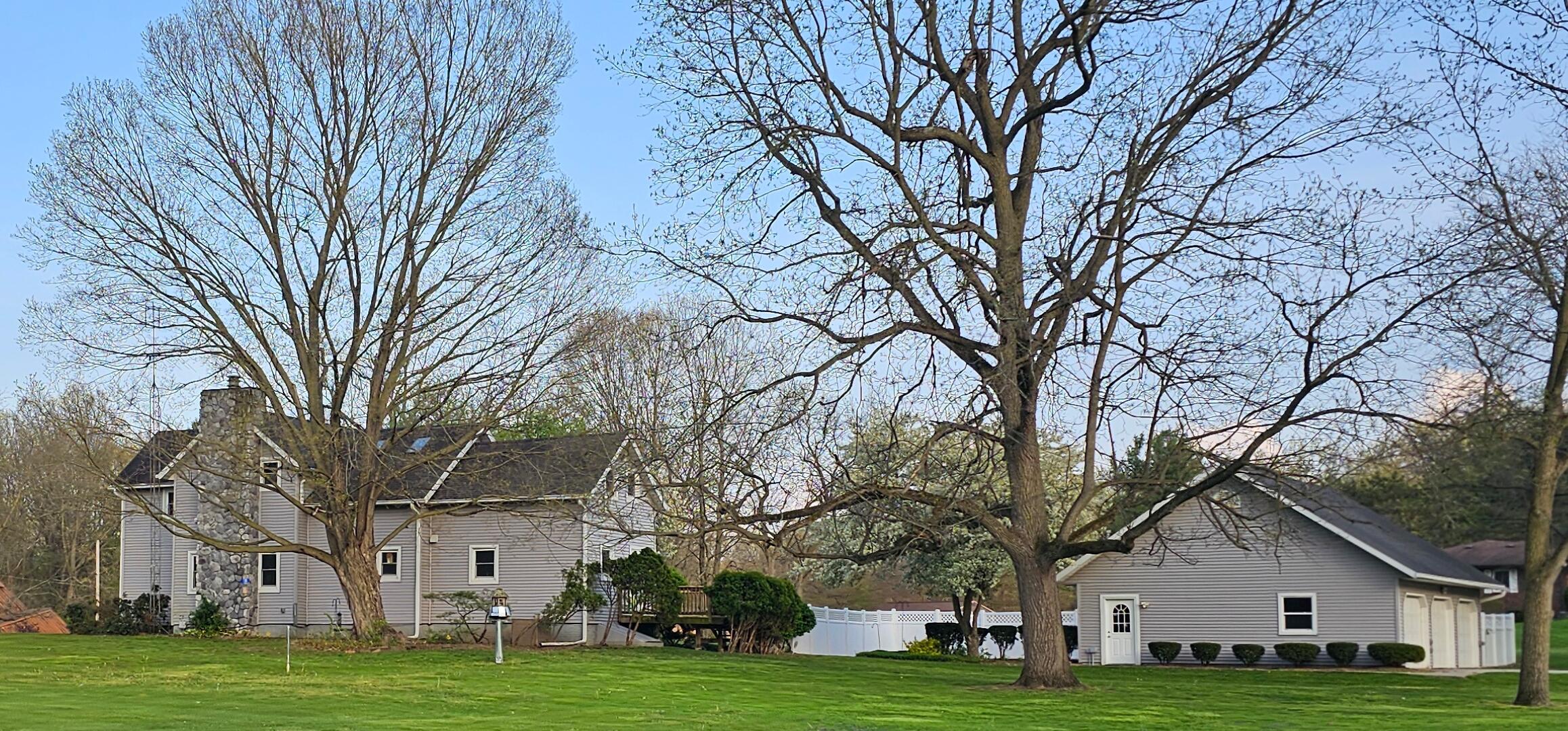 a view of a white house with a big yard and large trees