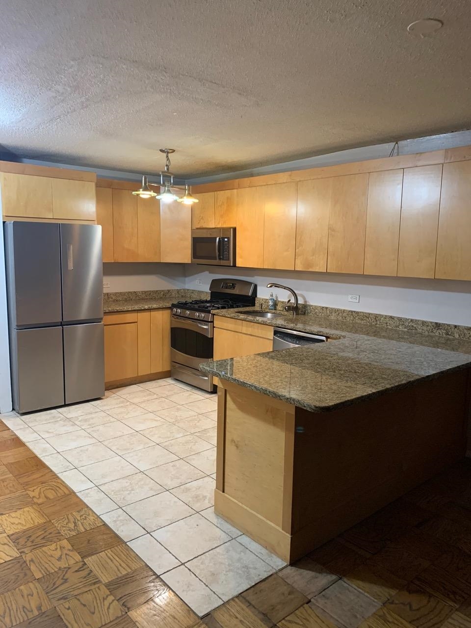 a kitchen with stainless steel appliances granite countertop a sink stove and refrigerator