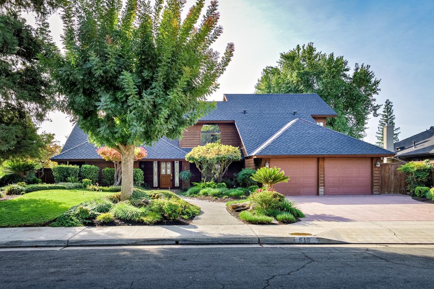 a front view of a house with plants and garage