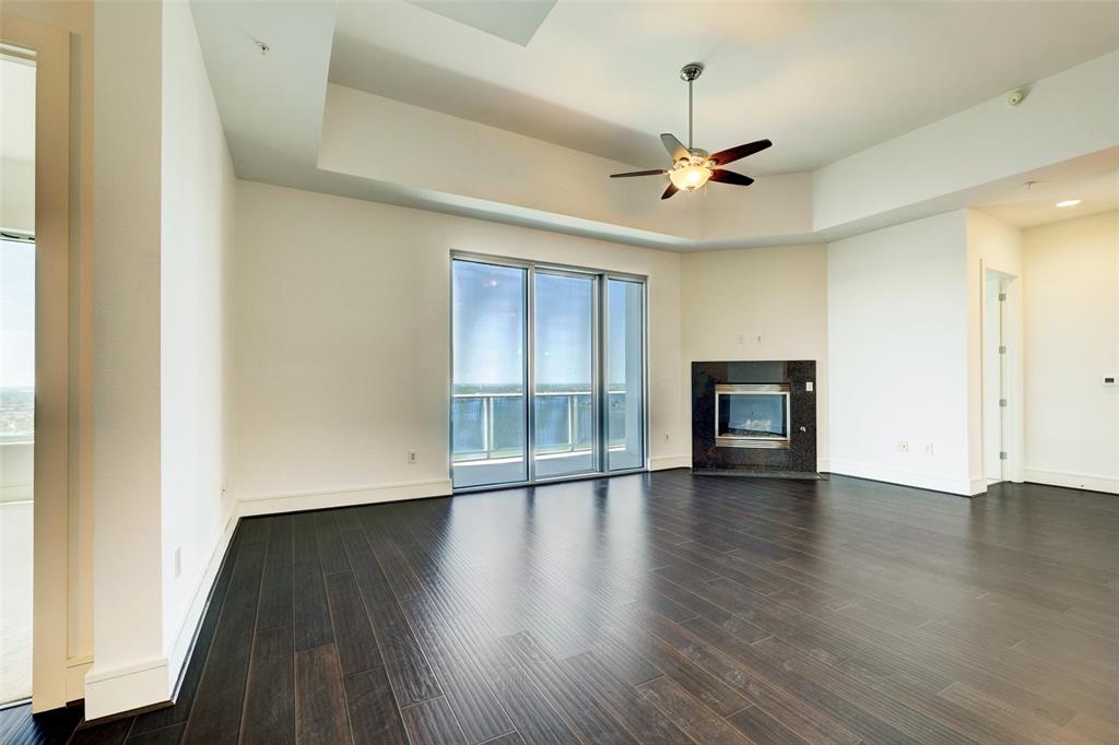 an empty room with wooden floor ceiling fan and windows