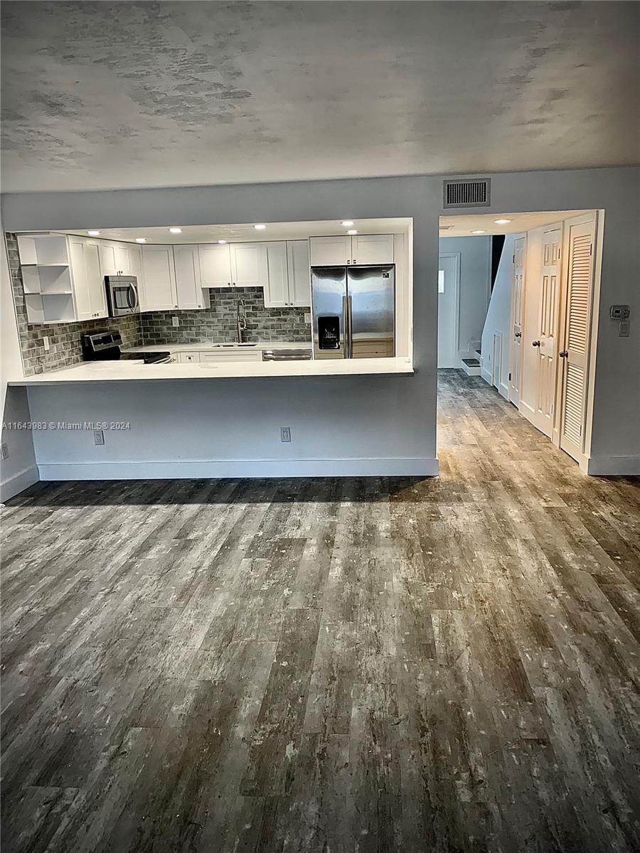 a kitchen with kitchen island granite countertop a sink stove and cabinets