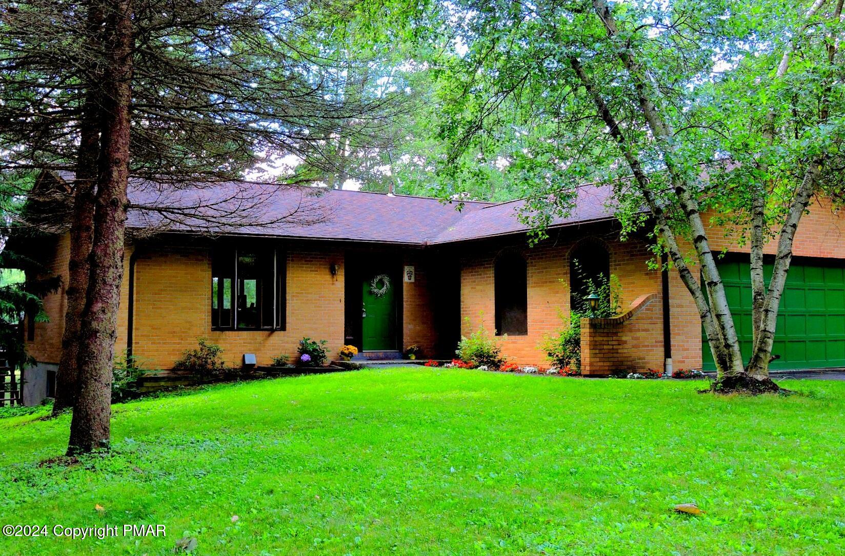 a front view of a house with a yard and a tree