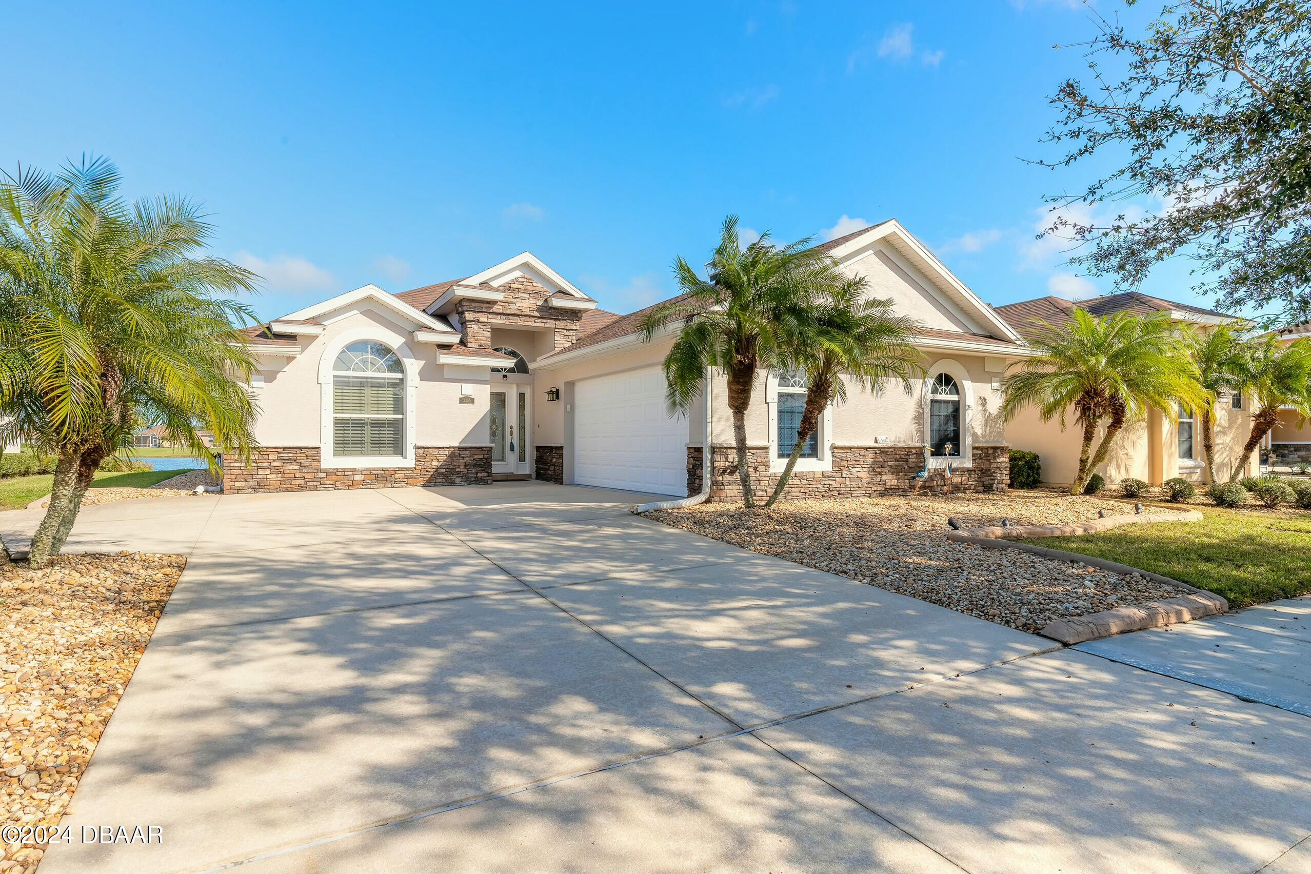 a view of a house with a yard and palm trees