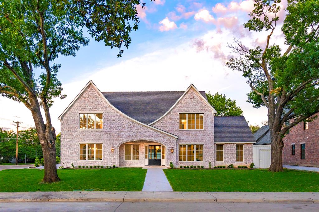 a view of a brick house next to a yard with big trees