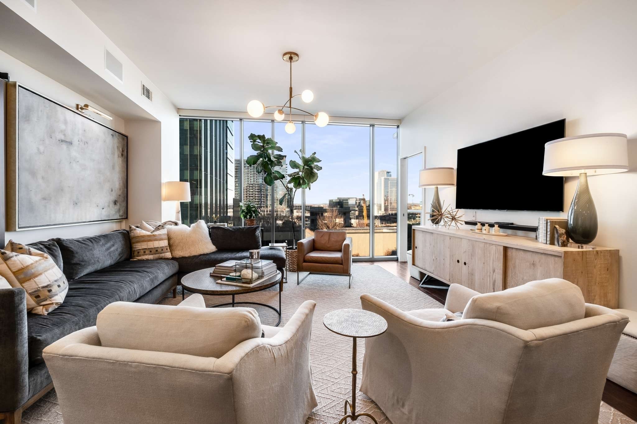 a living room with furniture a flat screen tv and a chandelier