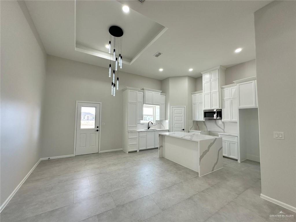 a large white kitchen with kitchen island a white counter space a sink and appliances