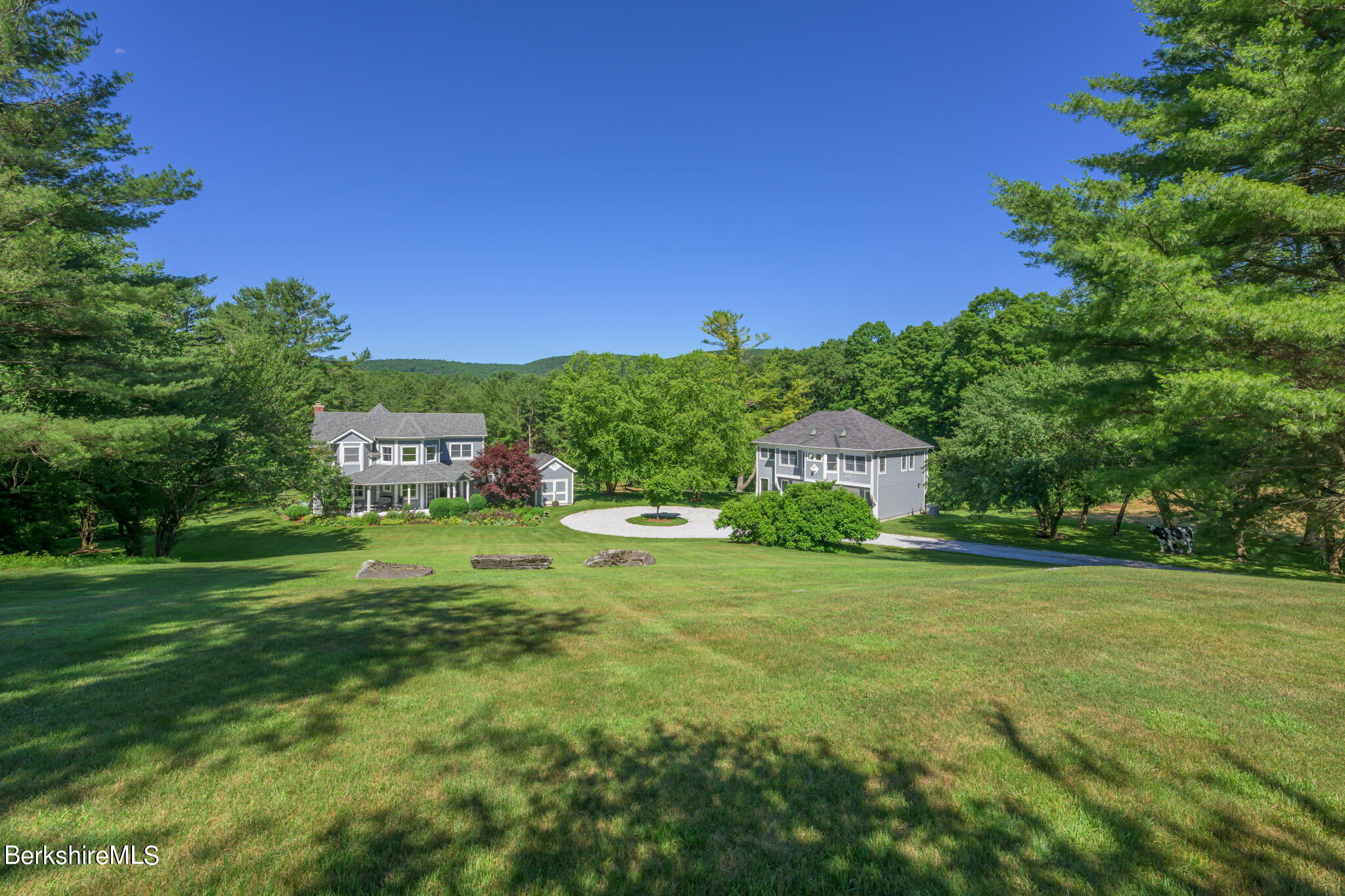 a view of a big house with a big yard and large trees