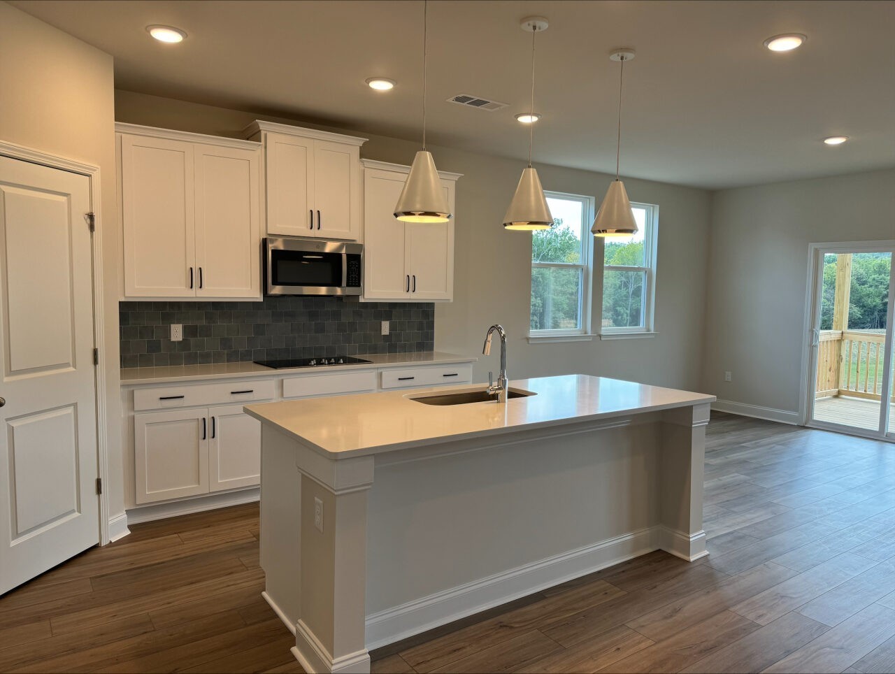 Kitchen with quartz counters, white cabinets and blue tile backsplash