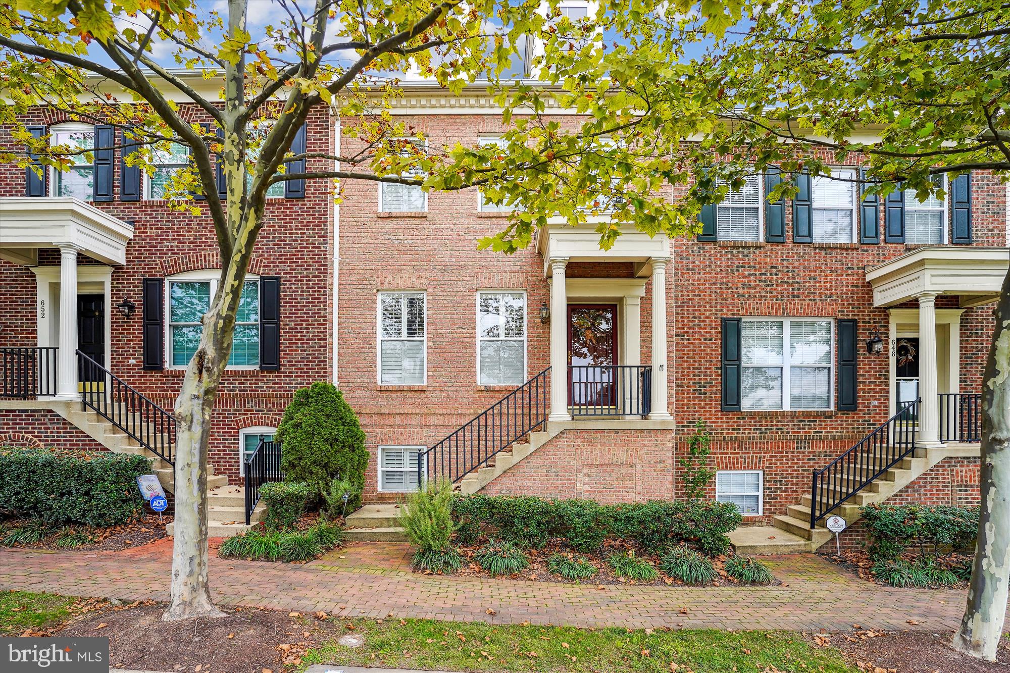 a front view of a brick house with a large windows and a tree