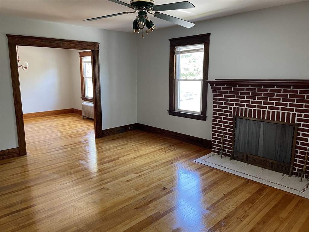 an empty room with wooden floor fan and windows