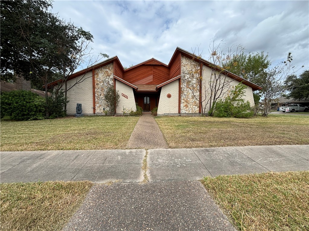 a view of a house with a yard and large tree