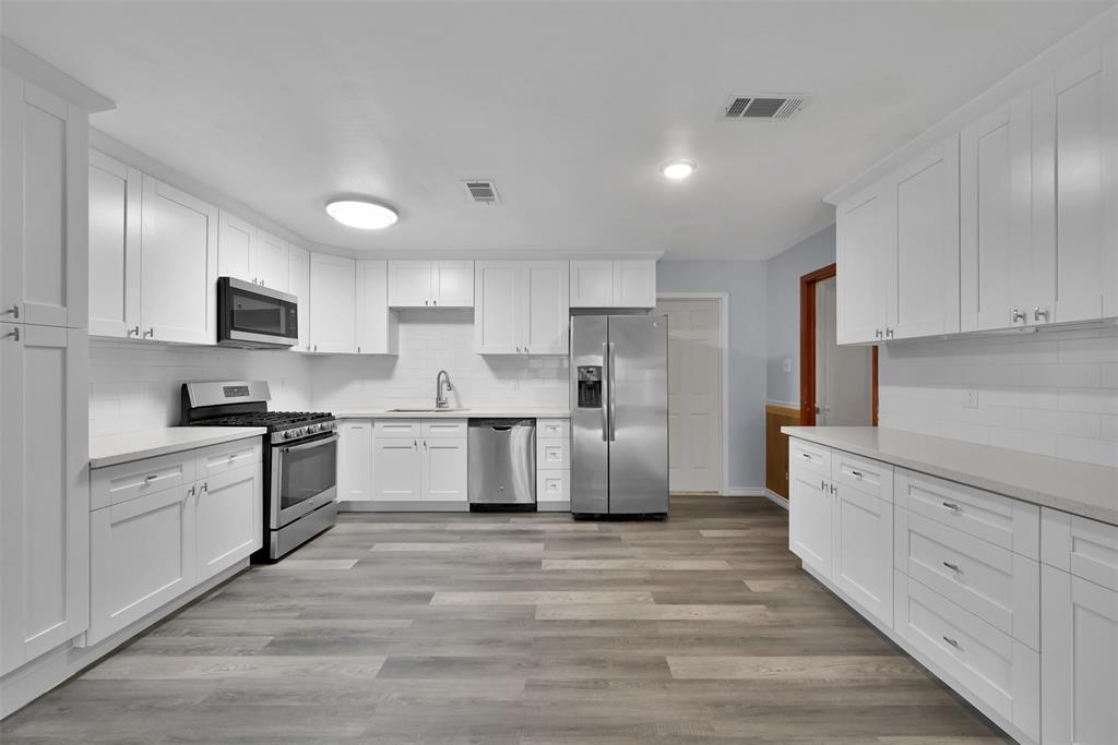 a large kitchen with cabinets wooden floor and stainless steel appliances