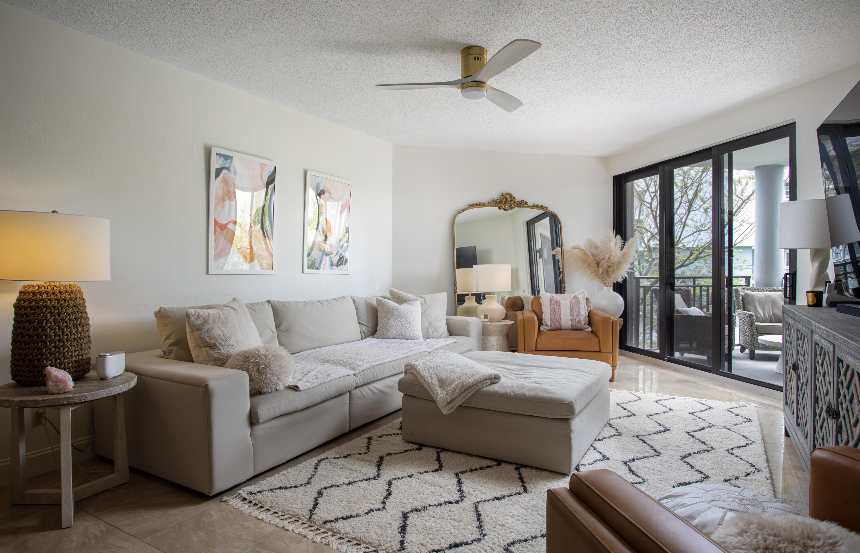 a living room with furniture a rug a lamp and a large window