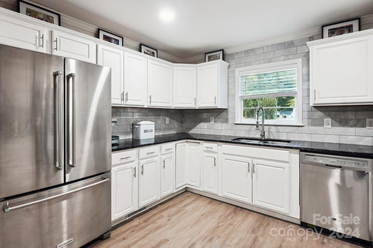 a kitchen with stainless steel appliances white cabinets a sink and a window