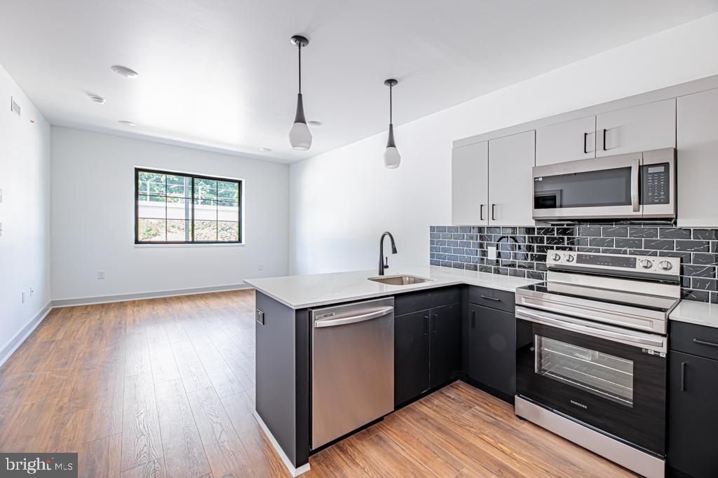 a kitchen with stainless steel appliances granite countertop a sink a stove a microwave and wooden floors