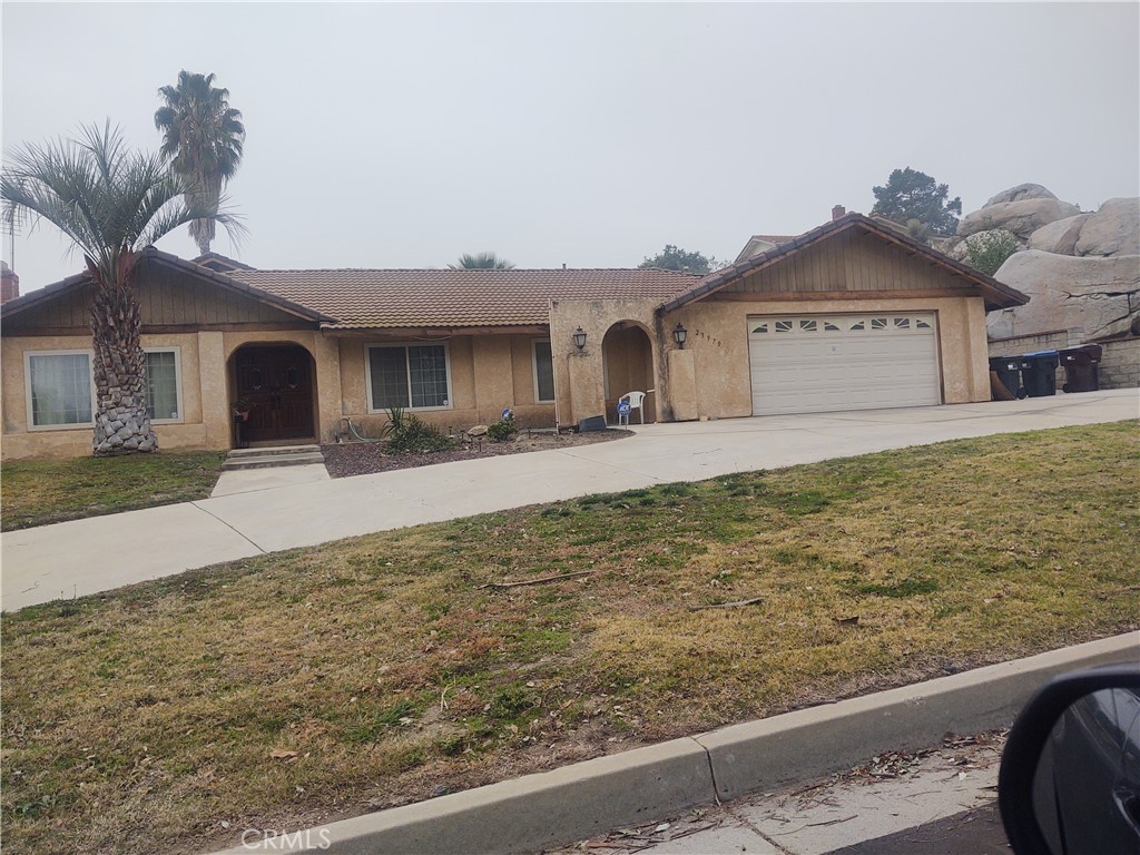 a front view of a house with yard and large tree