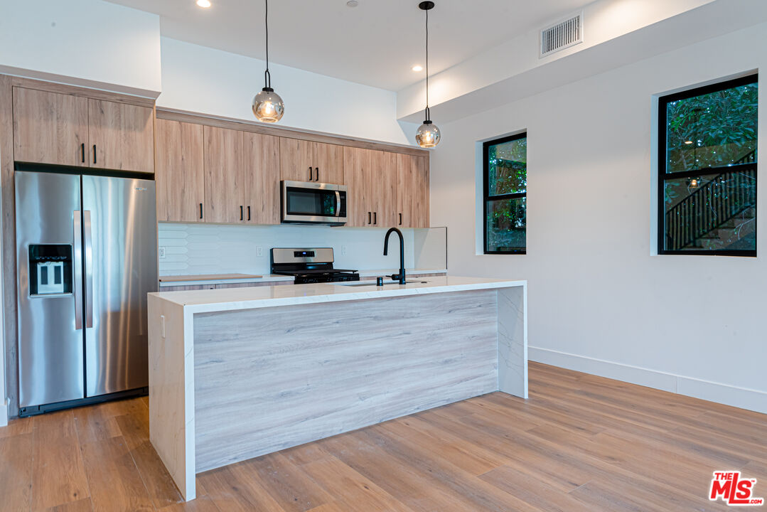 a kitchen with granite countertop a refrigerator and a stove top oven