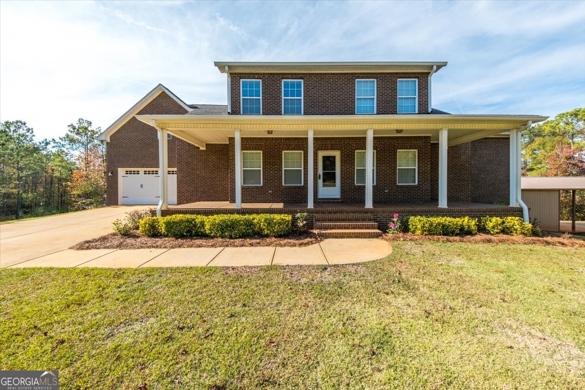 a front view of a house with yard and trees in the background