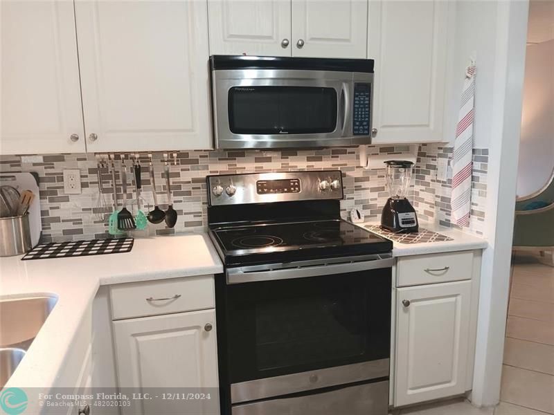 a kitchen with granite countertop a stove top oven microwave and cabinets