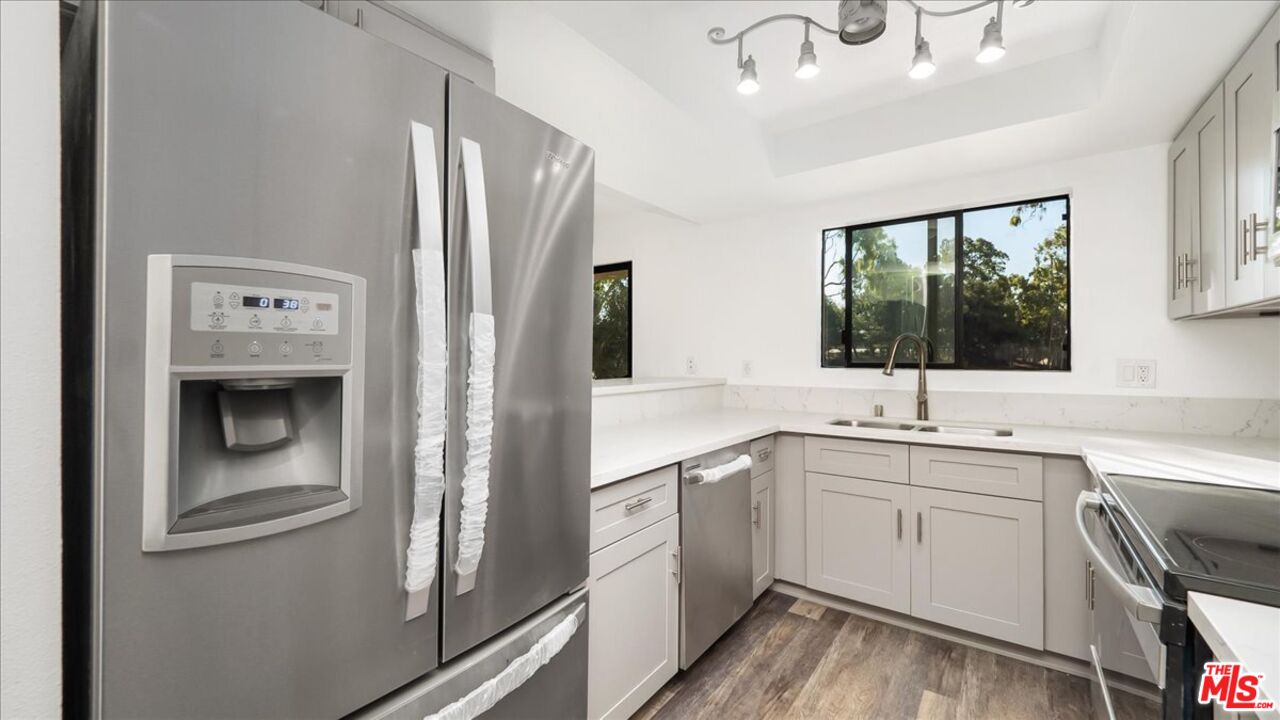 a kitchen with a sink cabinets stainless steel appliances and a window