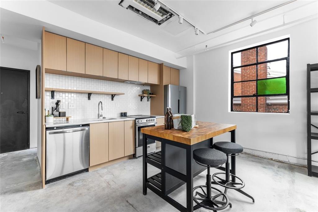 a kitchen with stainless steel appliances kitchen island a table chairs in it and wooden floors